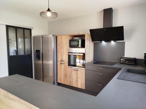 a kitchen with a stainless steel refrigerator and a microwave at Gite La grange bien être en baie du Mont St Michel in Bacilly