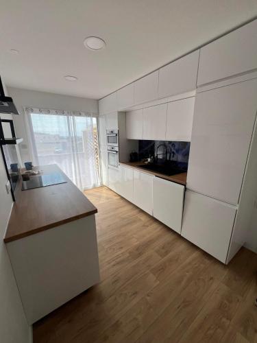 une cuisine avec des armoires blanches et un plancher en bois dans l'établissement L'azur Elite - T4 proche mer - Terrasse - Parking, à Sète