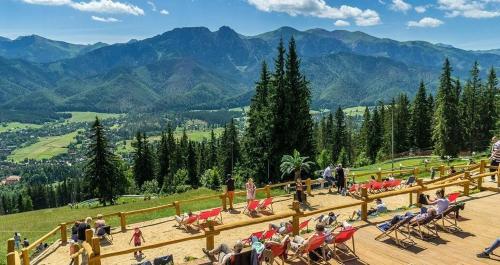 a group of people sitting on a deck overlooking the mountains at Krupówki 36 / 8a - Pokój 2 osobowy z widokiem na Giewont in Zakopane