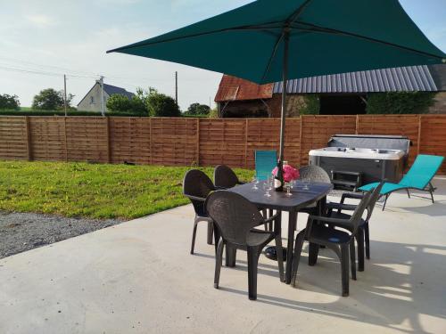 a table and chairs with an umbrella and a grill at Gite La grange bien être en baie du Mont St Michel in Bacilly