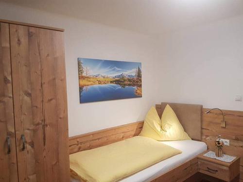 a room with a bed with a yellow pillow and a painting at No1 - Flo's Rooms & Breakfast in Wagrain