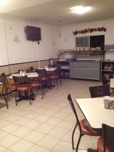 a dining room with tables and chairs and a kitchen at Hotel Santa Cruz in Chihuahua