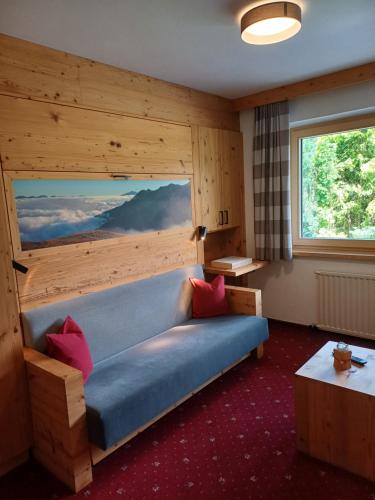 a living room with a blue couch and a window at Ferienwohnungen Lechthaler in Wenns
