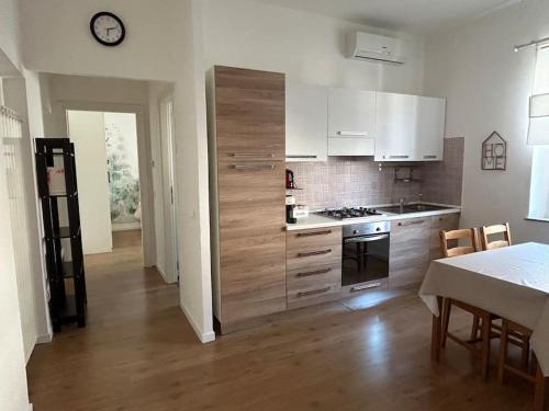 トレヴィニャーノ・ロマーノにあるCasa Vacanze Luisaの白いキャビネット、テーブル、時計付きのキッチン