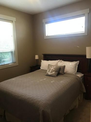 a bedroom with a large bed with two windows at Sooke Harbour Townhouse in Sooke