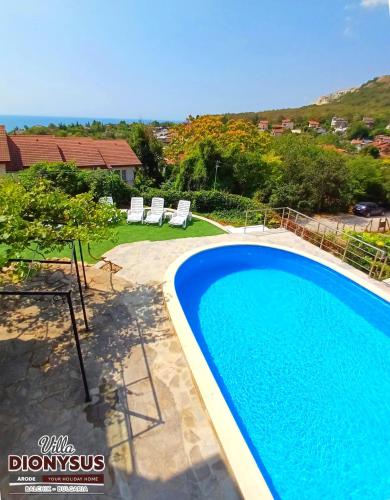 a swimming pool with two lawn chairs and a house at Arode Villa Dionysus in Balchik