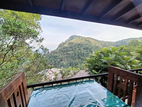 a table on a balcony with mountains in the background at Divine View Homestay in Ella
