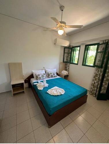 a bedroom with a bed with blue sheets and a fan at Zorbas Suites in Hersonissos