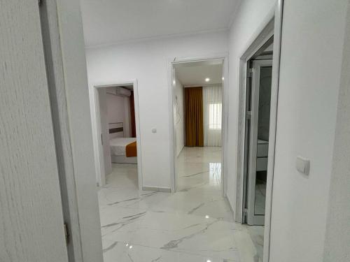 a white hallway with a mirror and a bedroom at Pami in Néa Péramos