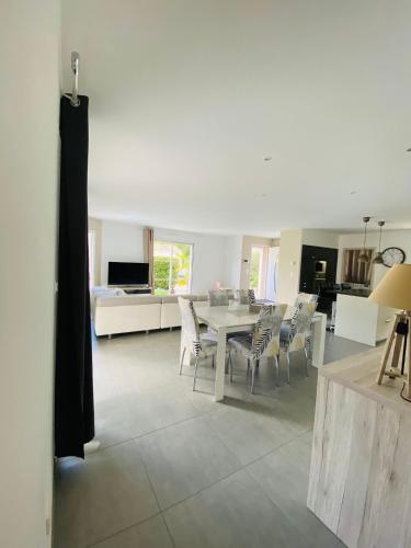 a living room with a dining room table and chairs at Villa Bassin d Arcachon 7pers piscine chauffée in Audenge