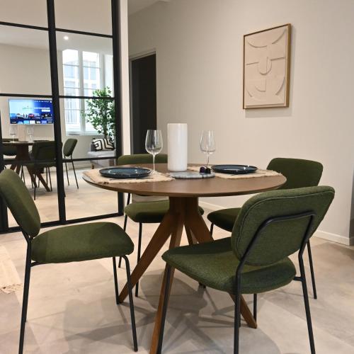 une salle à manger avec une table et des chaises vertes dans l'établissement Splendide Appartement haut de gamme hyper centre, à Marmande