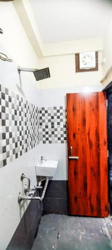 Un baño con puerta de madera y lavabo. en Vakratunda Home Stay, en Ujjain
