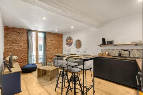 - une cuisine avec une table et quelques tabourets dans une pièce dans l'établissement Le Caraman Bohème - Confort à deux pas du métro, à Toulouse