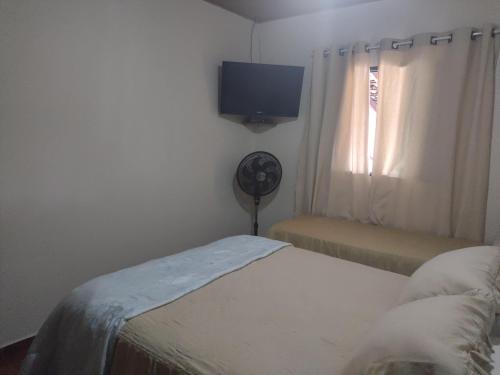 a bedroom with a bed and a tv and a window at Casa com pisina infantil em Brotas in Brotas