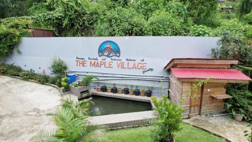 a sign that reads the white village next to a pond at TheMapleVillageFarmstay in Gangtok