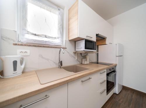 a kitchen with white cabinets and a sink and a window at Apartmani Sabbioso in Lopar