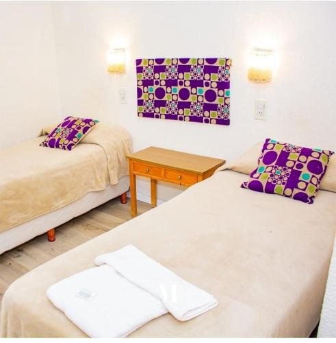 ein Zimmer mit zwei Betten und einem Holztisch in der Unterkunft HotelMora in Puerto Madryn