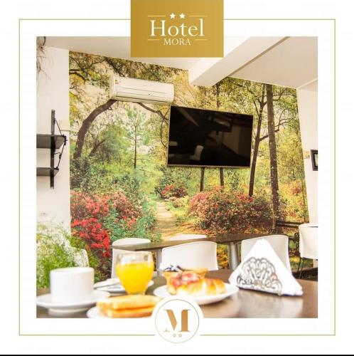 ein Tisch mit Essen darauf und einem Wandbild mit einem Wald in der Unterkunft HotelMora in Puerto Madryn