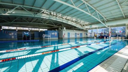 a large swimming pool with people standing in it at Happy Days Town House in Bridgend