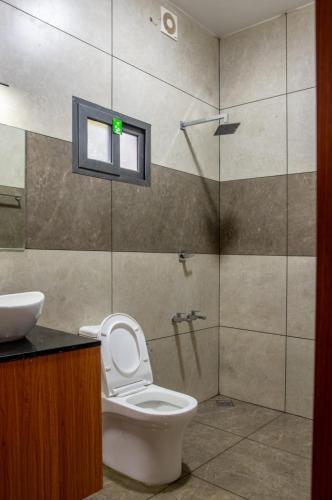 a bathroom with a toilet and a shower with a window at Vega Paradise in Kanthalloor