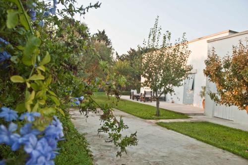 a garden with blue flowers and a sidewalk at Masseria Montelauro in Otranto