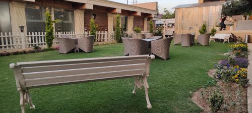 a park bench in a yard with chairs and tables at ARCO Hotels and Resorts Srinagar in Srinagar
