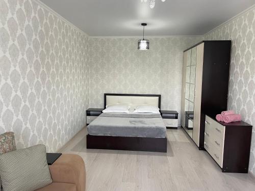 a bedroom with a bed and a chair and a couch at Уютная квартира-студия в Атырау ЖК MODERN SITY in Atyraū