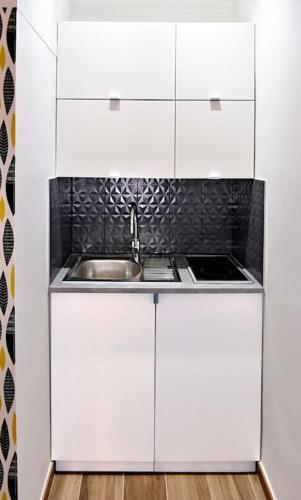 une cuisine avec des armoires blanches et un évier dans l'établissement Cosy studio LEMONADE in Bastille, à Paris