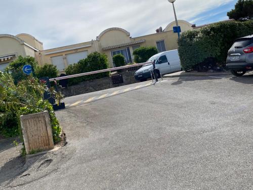 un parking avec des voitures garées devant un bâtiment dans l'établissement Annyck, à Gruissan