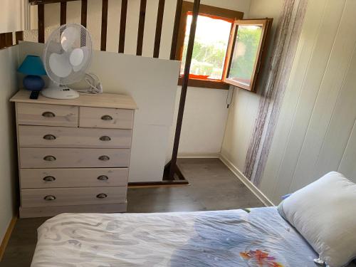 - une chambre avec un lit et une commode avec un ventilateur dans l'établissement Annyck, à Gruissan