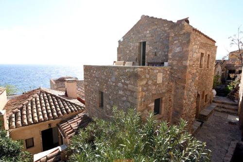 an old stone building with the ocean in the background at Milonas Guest House in Monemvasia