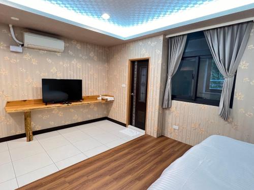 a bedroom with a bed and a tv on a wall at 微楓民宿 可加購晚餐酸白菜火鍋 in Renai