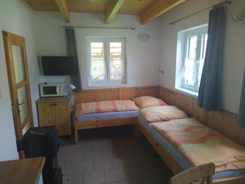 a room with two beds and a tv and two windows at Komplex Apartmánů Jestřábí in Černá v Pošumaví