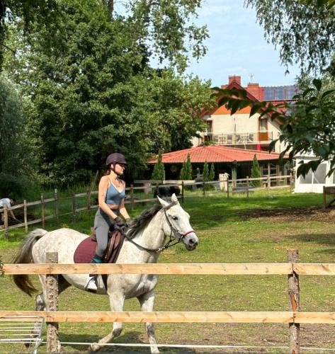 a woman riding a horse near a fence at Folwark Nadmorska Ostoja in Mechelinki