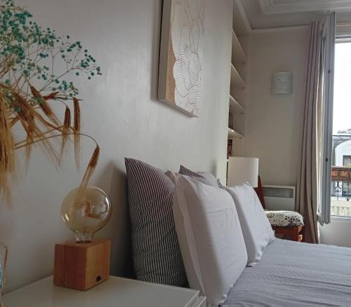 une chambre avec un lit avec des draps blancs et des oreillers dans l'établissement Appartement avec balcon au cœur PARIS, à Paris