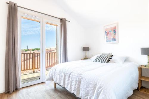 Appartement à 200 m de la plage في ميميزان: غرفة نوم بيضاء مع سرير وشرفة