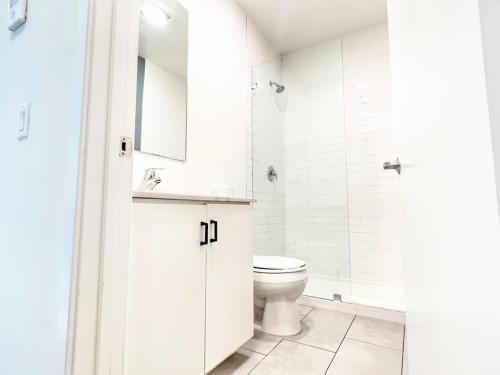 Un baño blanco con inodoro y lavabo. en Grand Downtown San Diego Apartment, en San Diego