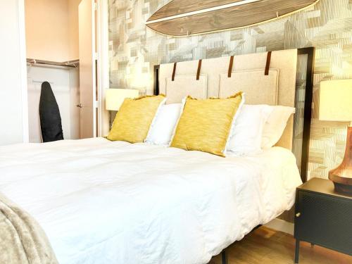 Un dormitorio con una gran cama blanca con almohadas amarillas. en San Diego Skyline - Downtown Apartment, en San Diego