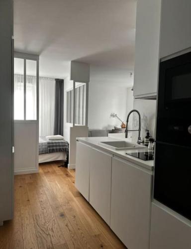 une cuisine avec des armoires blanches et un évier et un évier dans l'établissement appart avec piscine casino plein air et plage, à La Ciotat