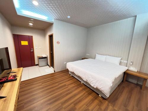 a bedroom with a large white bed and a desk at 微楓民宿 可加購晚餐酸白菜火鍋 in Renai