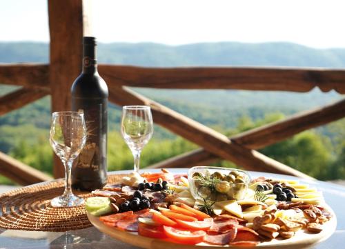 a plate of food and two wine glasses on a table at Relax house Aurora in Jasenovica