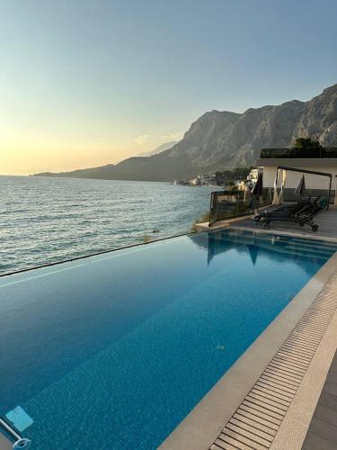 a large swimming pool next to a body of water at ADRIA MIRIS apartments in Drasnice