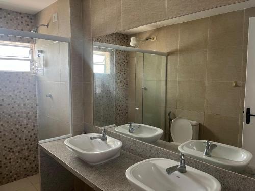 a bathroom with three sinks and a mirror and a toilet at Casa em Ilha de Itamaracá in Itamaracá