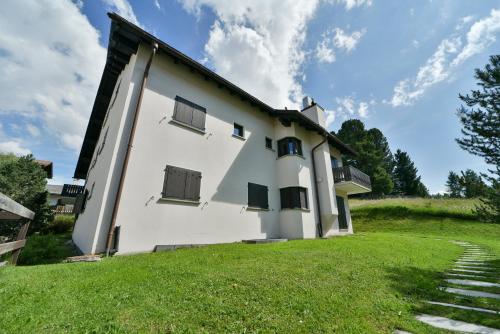 a large white building with a grass yard at Chesa Al Munt - Celerina in Celerina