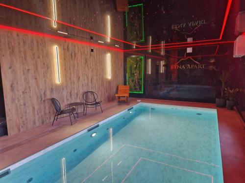 a swimming pool with two chairs and a table at Etna Apart in Łeba