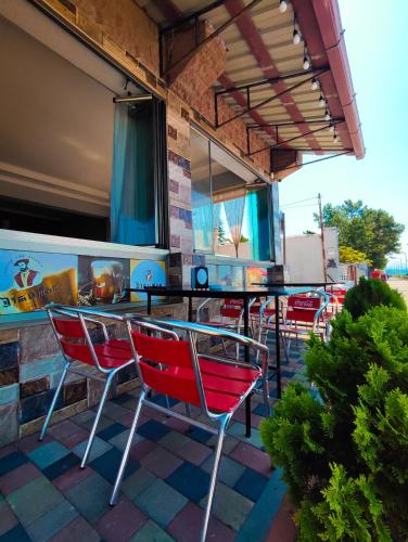 a patio with red chairs and a glass table at Guest House Rusalka in K'obulet'i