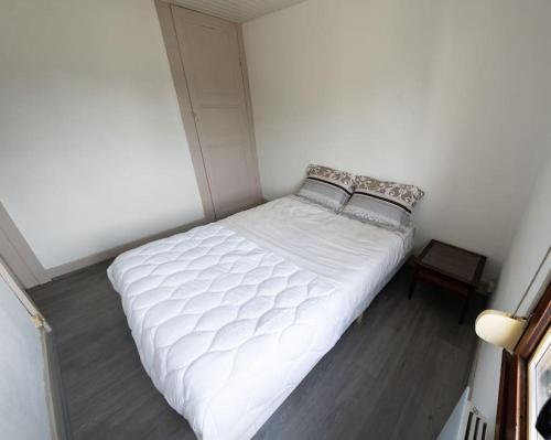 Ce lit se trouve dans une petite chambre dotée d'un couvre-lit blanc. dans l'établissement Duplex calme proche centre-ville, à Saint-Dizier