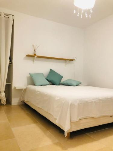 - une chambre blanche avec un lit et des oreillers bleus dans l'établissement T2 cosy tout équipé avec terrasse plancha, à Montauroux