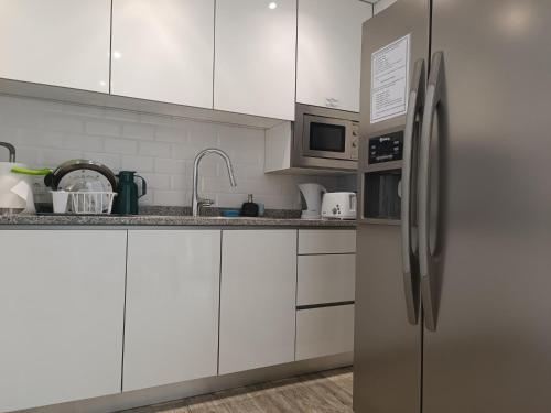 a kitchen with white cabinets and a stainless steel refrigerator at Cachinnans Hostel & Apartments in Vila do Conde
