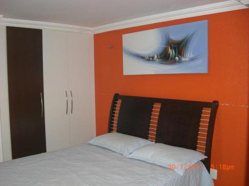 1 dormitorio con 1 cama con pared de color naranja en Apartamento na Praia do Futuro, en Fortaleza